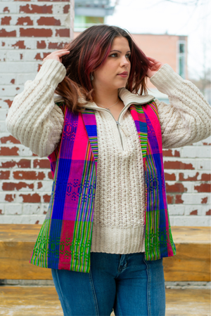 Model wearing a Latin-inspired, artisan-made, semi-fitted, colorful vest handwoven in El Salvador with a collar over a creamy sweater 